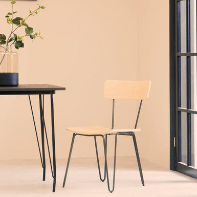 Modern chair with black metal legs and beige seat in a minimalistic room.