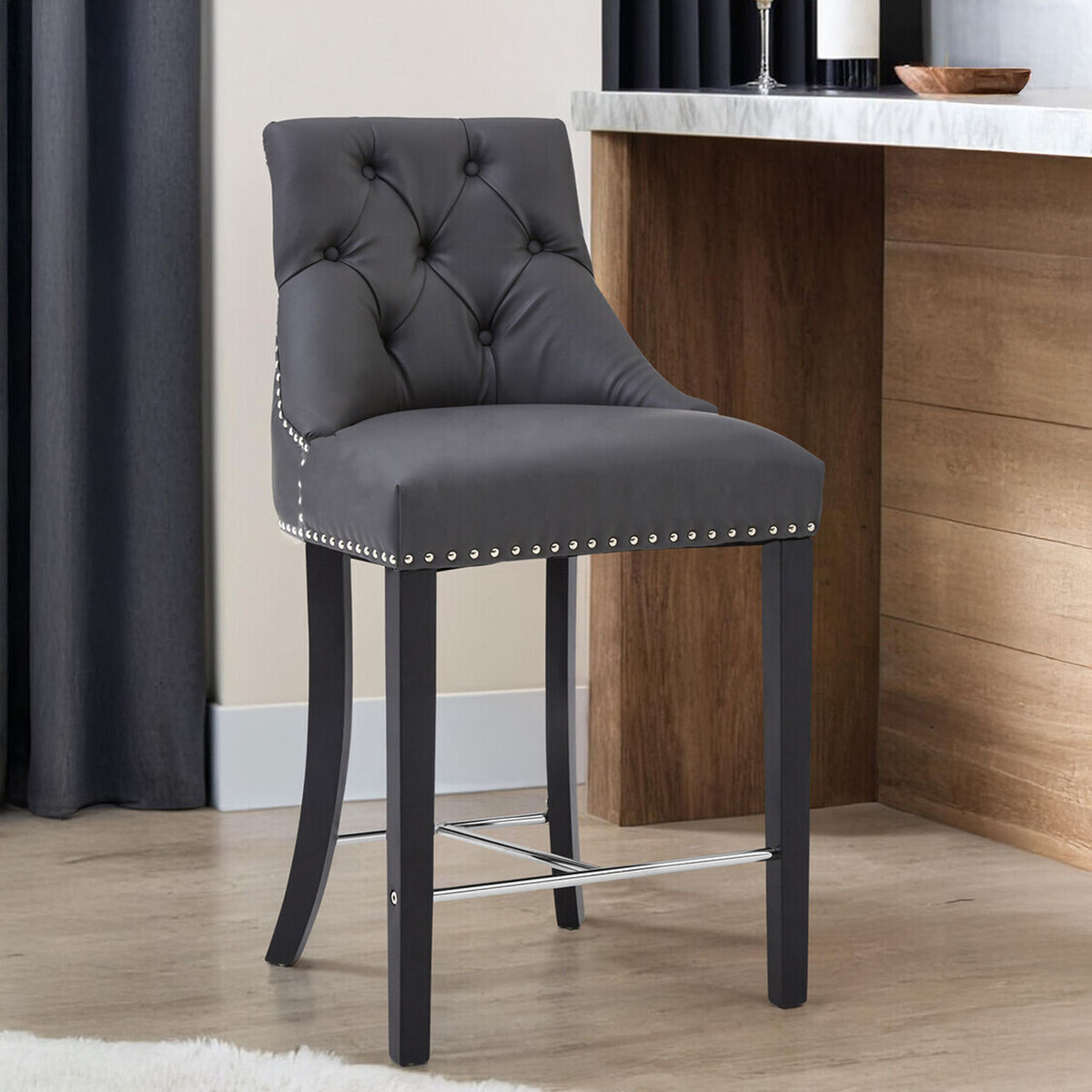 Gray bar stool with tufted backrest and nailhead trim in a room setting.