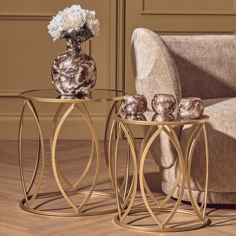 Gold side table with decorative items next to a beige sofa in a room with brown walls.