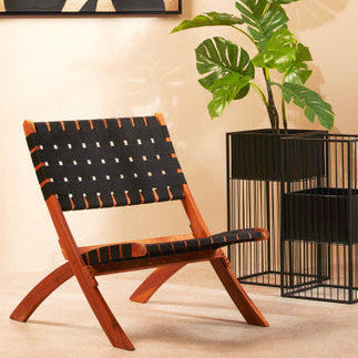 Modern chair with woven backrest in a room with a plant and abstract wall art.