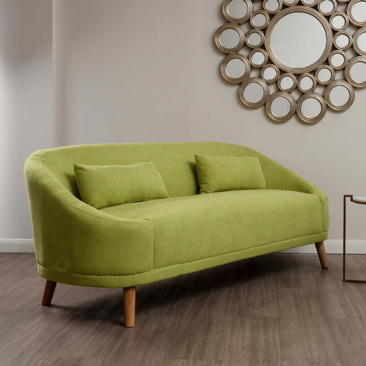 Green sofa in a room with a decorative mirror on the wall.