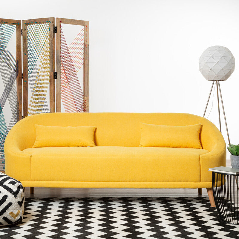 Yellow sofa in a room with a patterned rug, side table, and decorative screen.