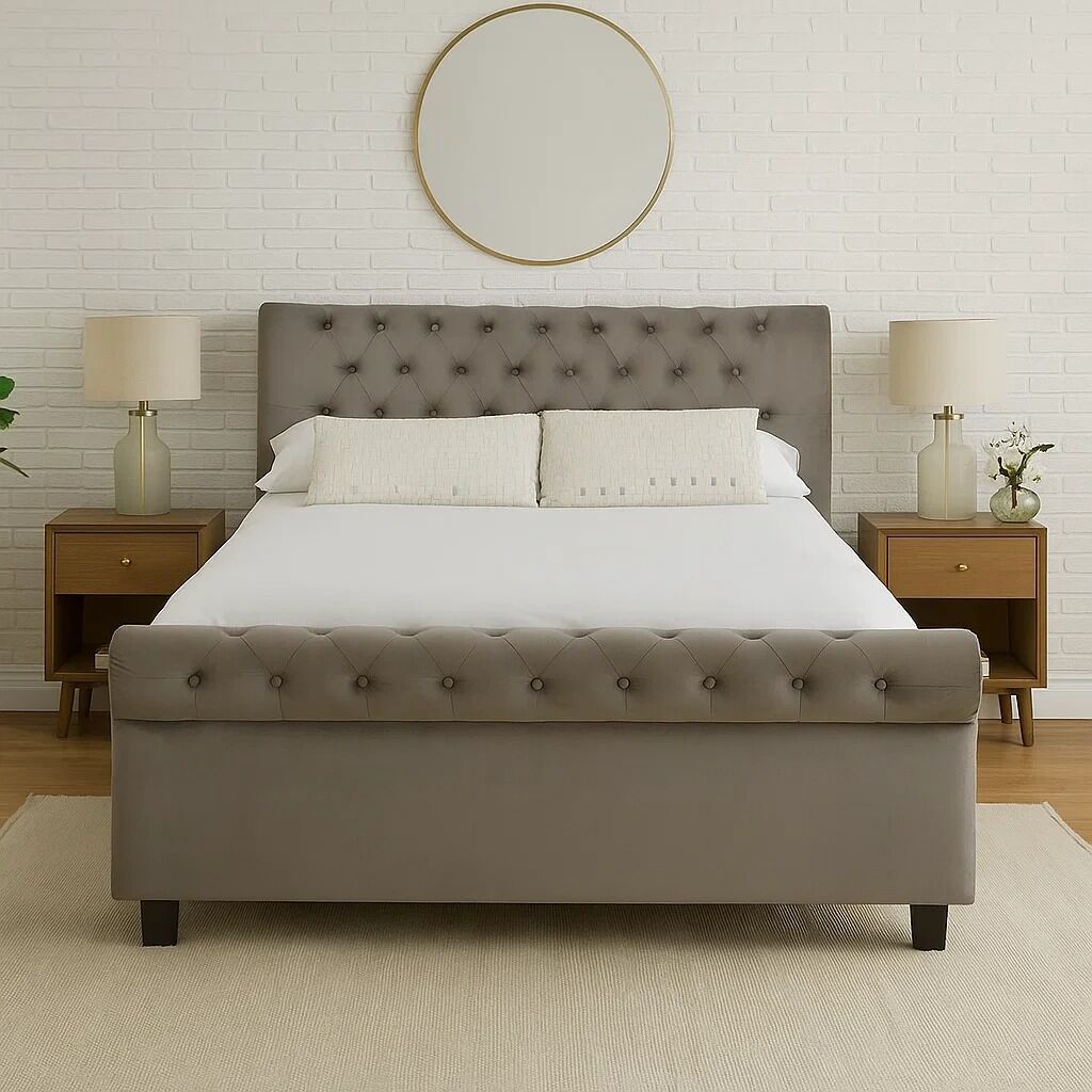Gray tufted bed with white bedding in a bedroom setting with lamps and decor.