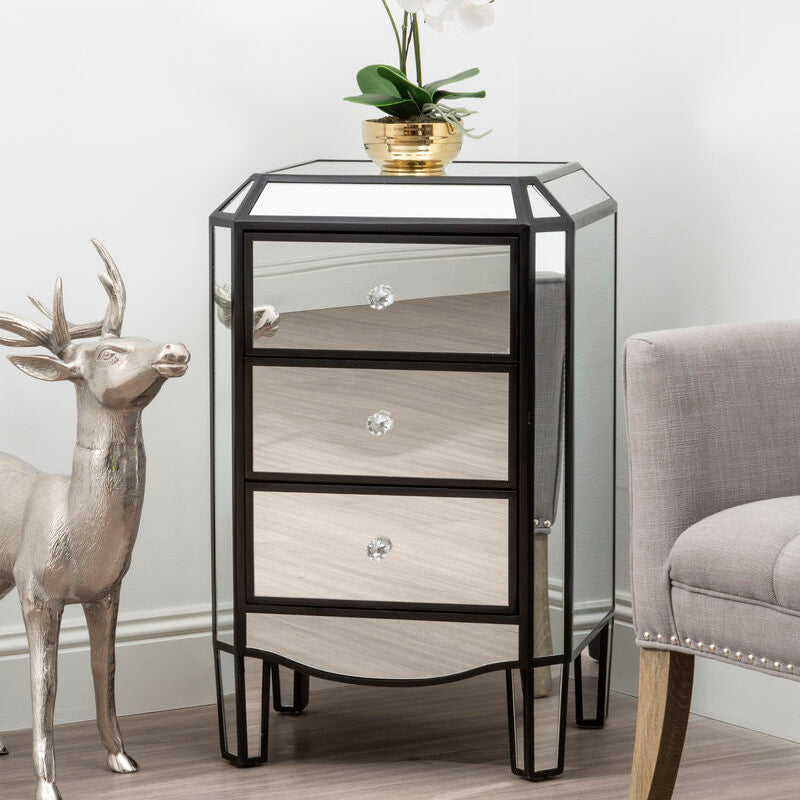 Decorative side table with glass top and wooden drawers in a room setting.