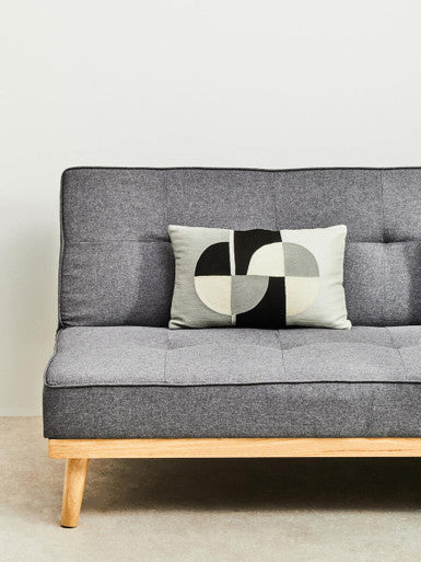Gray sofa with a wooden frame and a decorative pillow featuring geometric patterns.