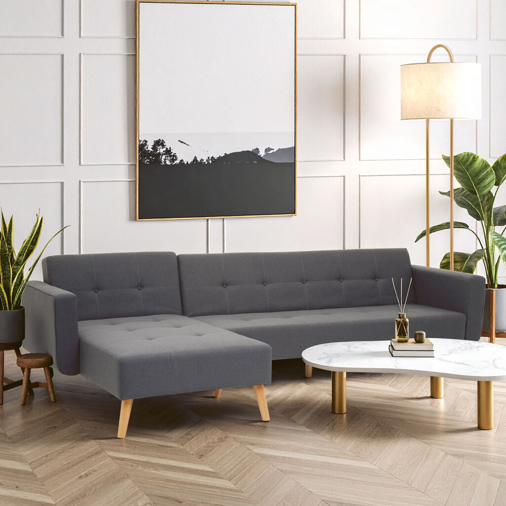 Modern living room with a gray sectional sofa, white coffee table, and decorative plants.