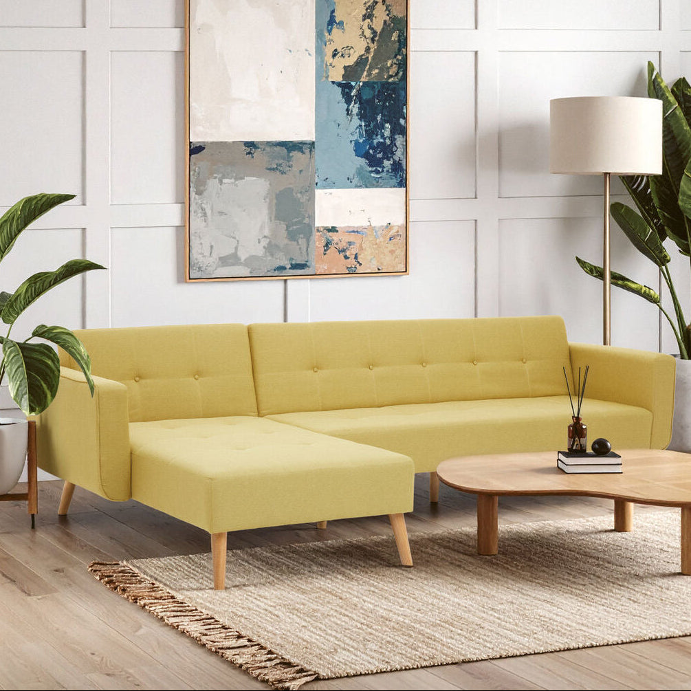 Modern living room with a yellow sectional sofa, wooden coffee table, and decorative plants.