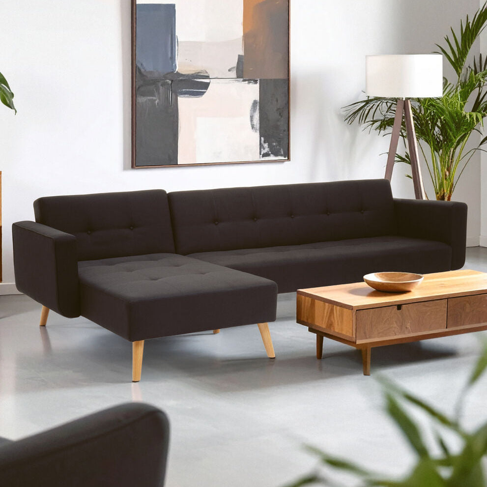 Modern living room with a black sofa, wooden coffee table, and abstract art on the wall.