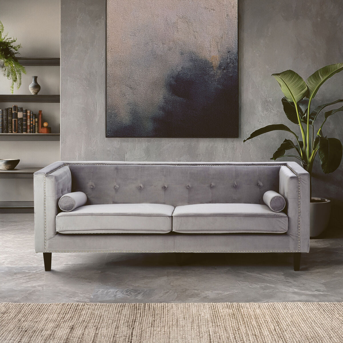 Gray sofa in a living room setting with a painting and plants on the wall.