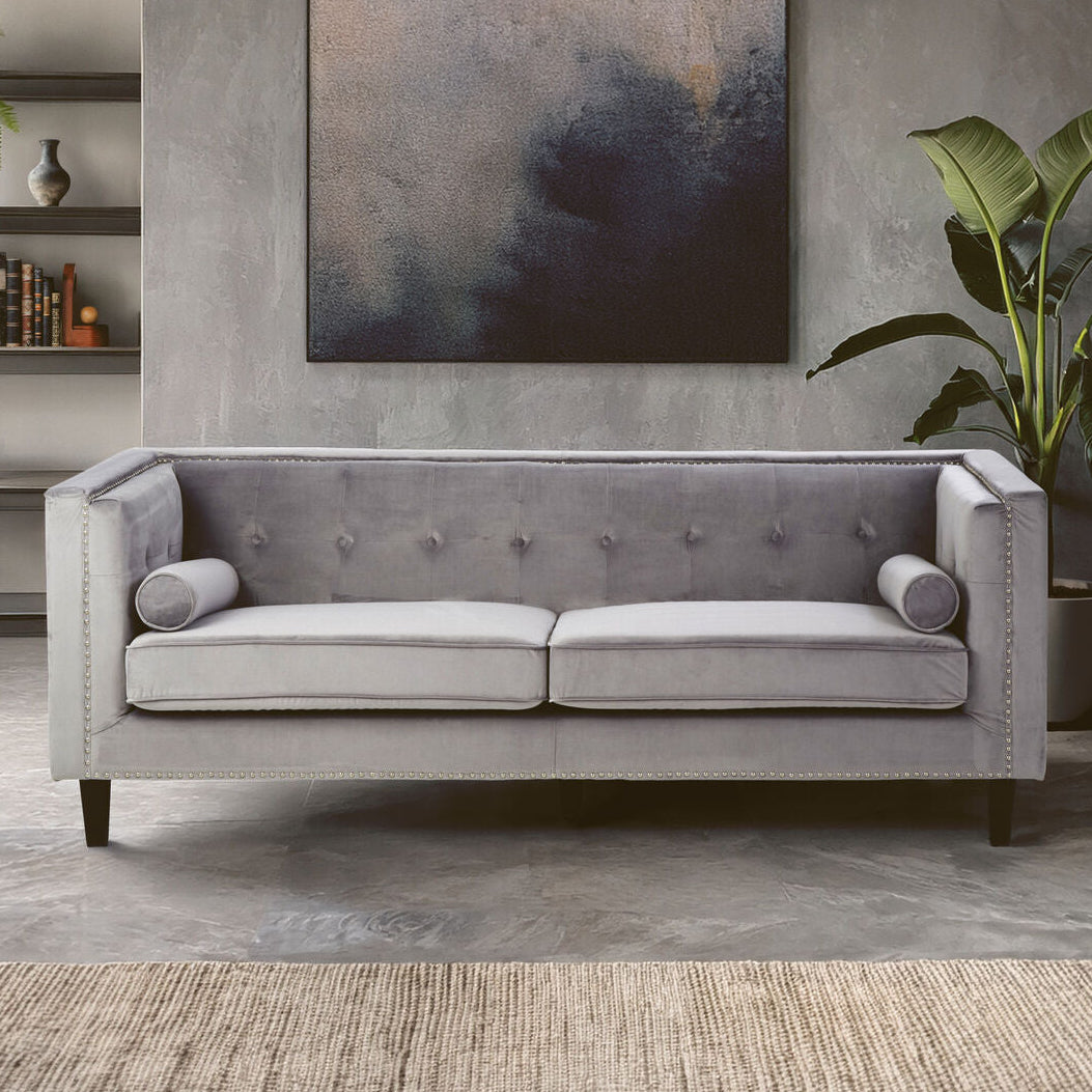 Gray sofa in a living room setting with a painting and plants on the wall.