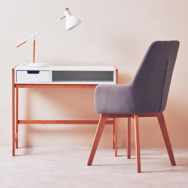 Minimalist desk with a chair and lamp against a plain wall.