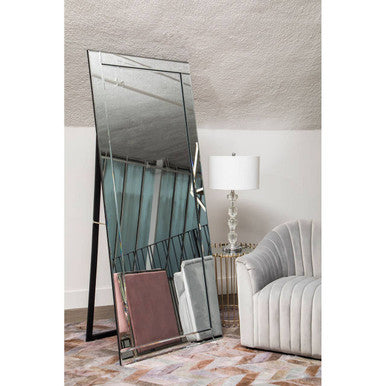 Tall floor mirror with geometric design in a room with a lamp and chair.