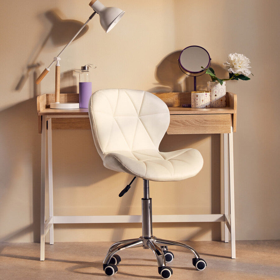 White office chair in front of a wooden desk with a lamp and decorative items.