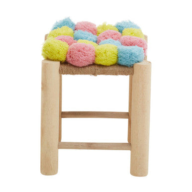 Wooden stool with a colorful pom-pom cushion on a white background