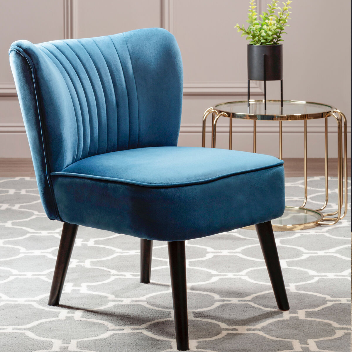 Blue velvet chair in a room with a patterned rug and small table.