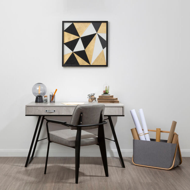 Modern office desk with chair and storage bin against a white wall with a geometric art piece.