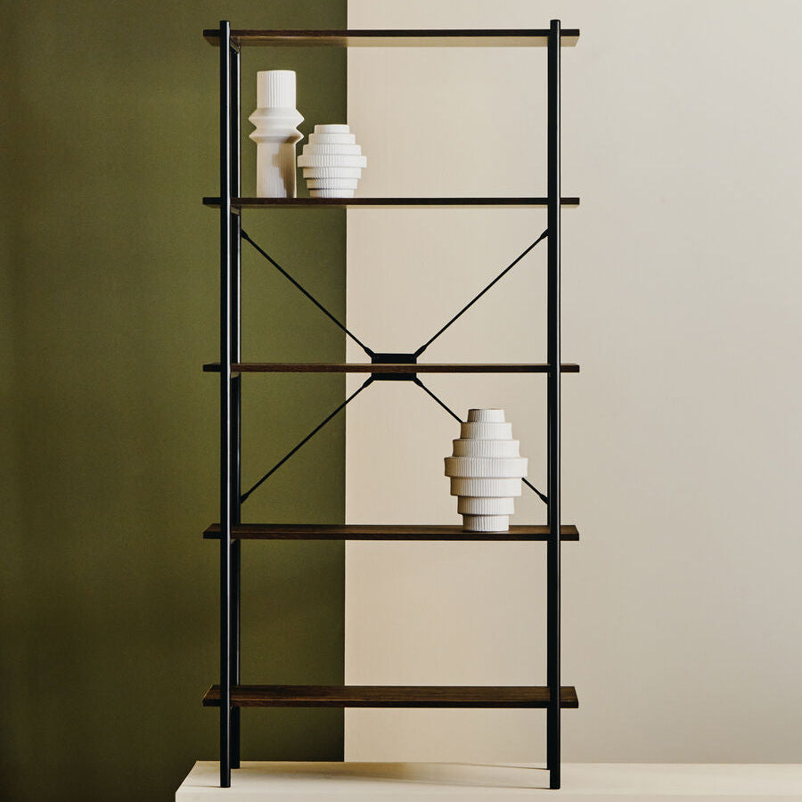 Black metal shelf with white ceramic vases against a green and beige wall.