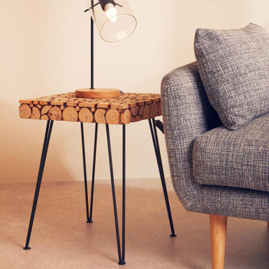 Small side table with woven top and black metal legs next to a gray sofa.