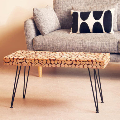 Wooden coffee table with unique design in front of a gray sofa with a decorative pillow.