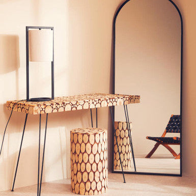 Wooden console table with patterned legs and stool against a beige wall with a large mirror.