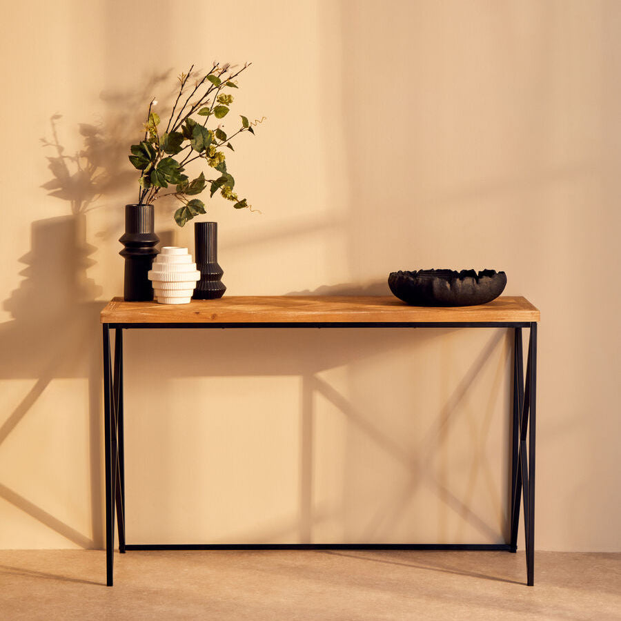 Wooden console table with decorative items against a beige wall