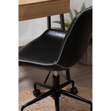 Black office chair with a wooden desk and plant in the background