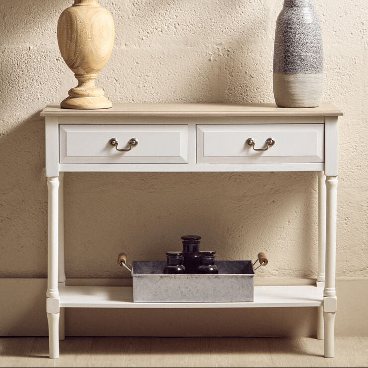 White console table with a lamp, vase, and decorative items against a beige wall.