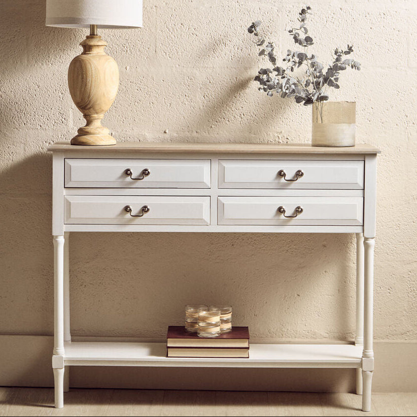 White console table with a lamp, books, and decorative items against a beige wall.