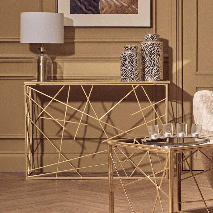 Modern living room with gold geometric console table and side table, gray sofa, and abstract art.