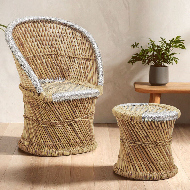Wicker chair and ottoman set with a plant and wooden table in the background.