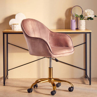 Pink velvet chair in front of a wooden desk with decorative items on a beige background