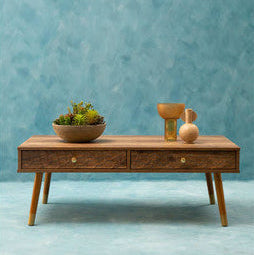Wooden coffee table with decorative items against a blue wall