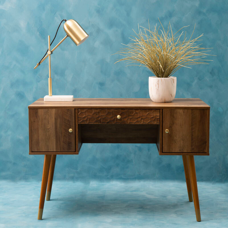 Wooden desk with a lamp and plant against a blue wall