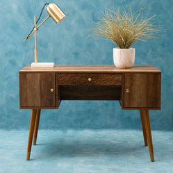 Wooden desk with a lamp and plant against a blue wall