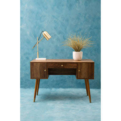 Wooden desk with a lamp and plant against a blue wall