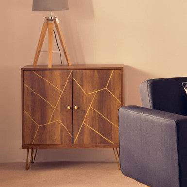 Wooden cabinet with geometric design next to a gray armchair and tripod lamp against a beige wall.