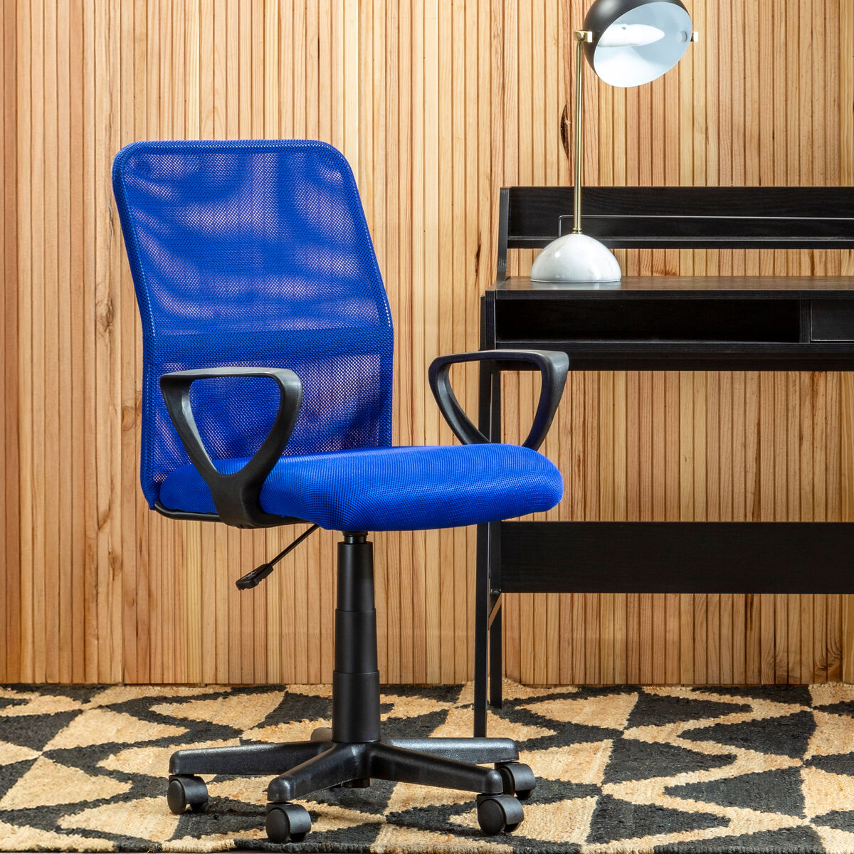 Blue office chair in front of a wooden desk with a lamp.