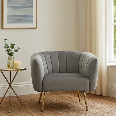 Gray armchair in a room with a side table, candle, and plant.