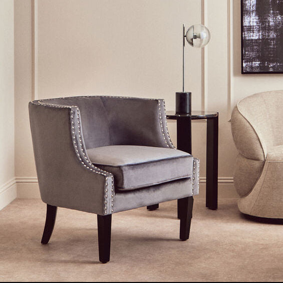 Modern living room with gray armchair, beige sofa, and abstract art on the wall.
