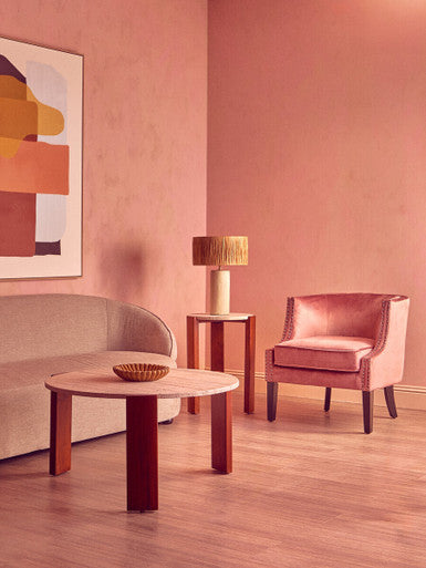 Modern living room with pink walls, a sofa, coffee table, and chair.