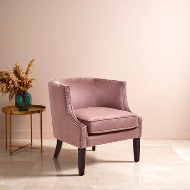 Pink armchair in a room with a small table and decorative elements.