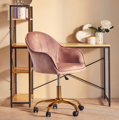 Pink office chair in front of a wooden desk with decorative items on a beige wall background