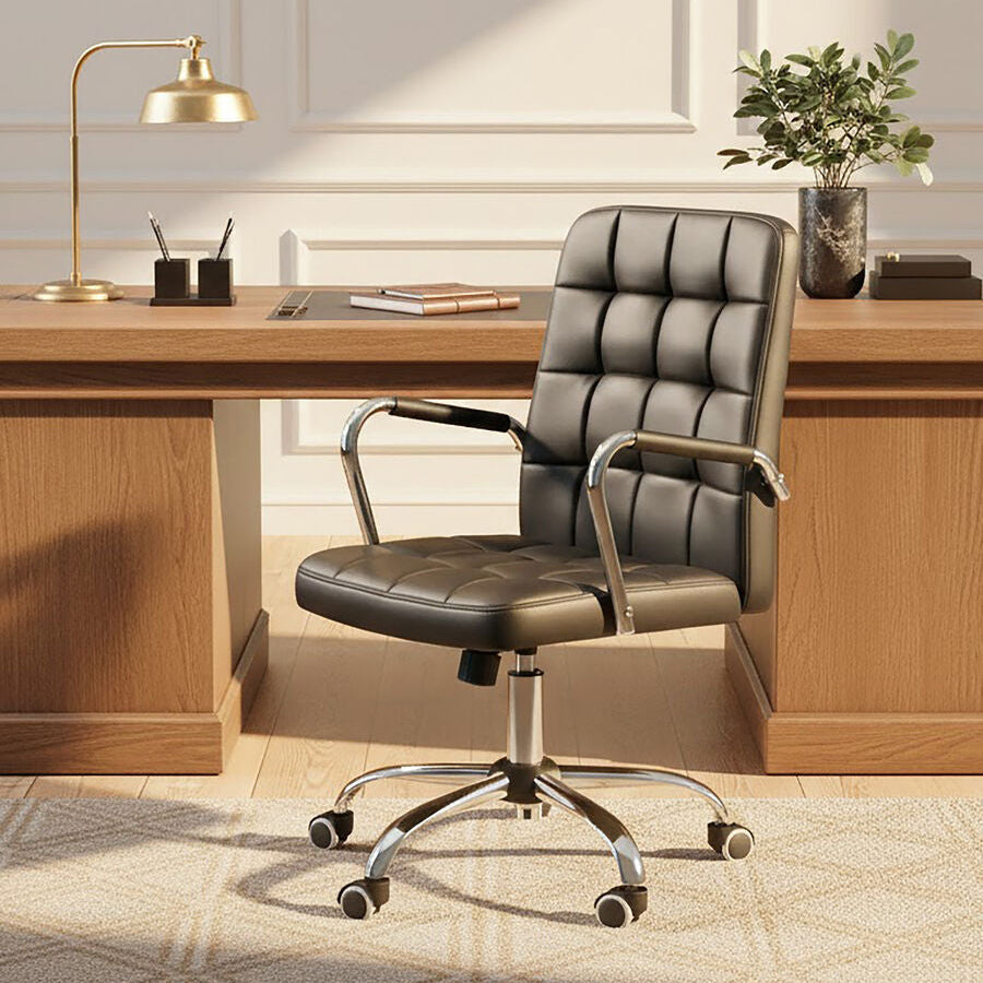 Modern office desk with a black office chair, lamp, and decor.