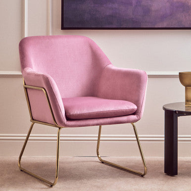 Pink velvet armchair with gold legs in a room setting