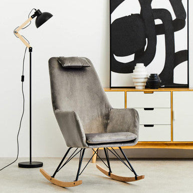 Gray rocking chair in a modern living room with abstract art and floor lamp.
