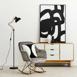Modern interior with a sideboard, chair, and abstract art on a white wall.