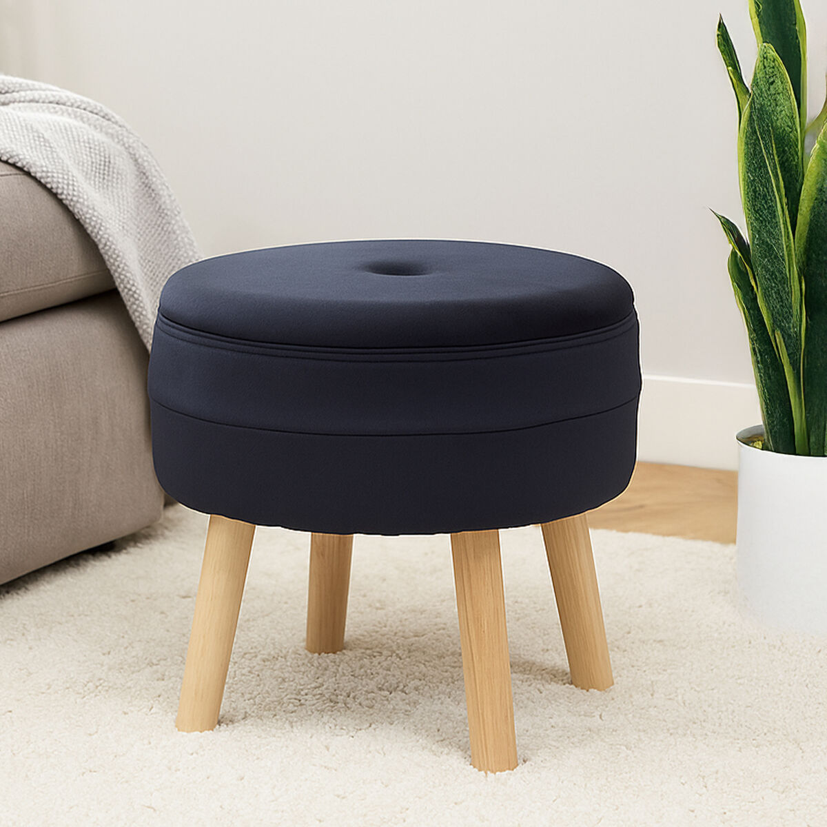 Navy blue ottoman with wooden legs in a living room setting