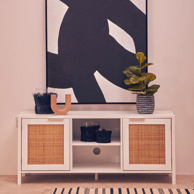 White cabinet with wicker doors against a wall with abstract art