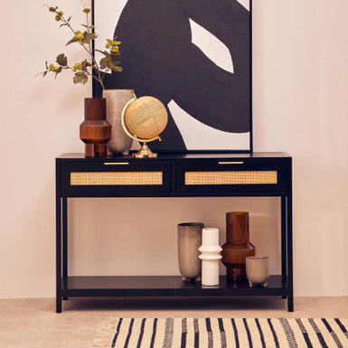Console table with decorative items and a large abstract painting on a beige wall.