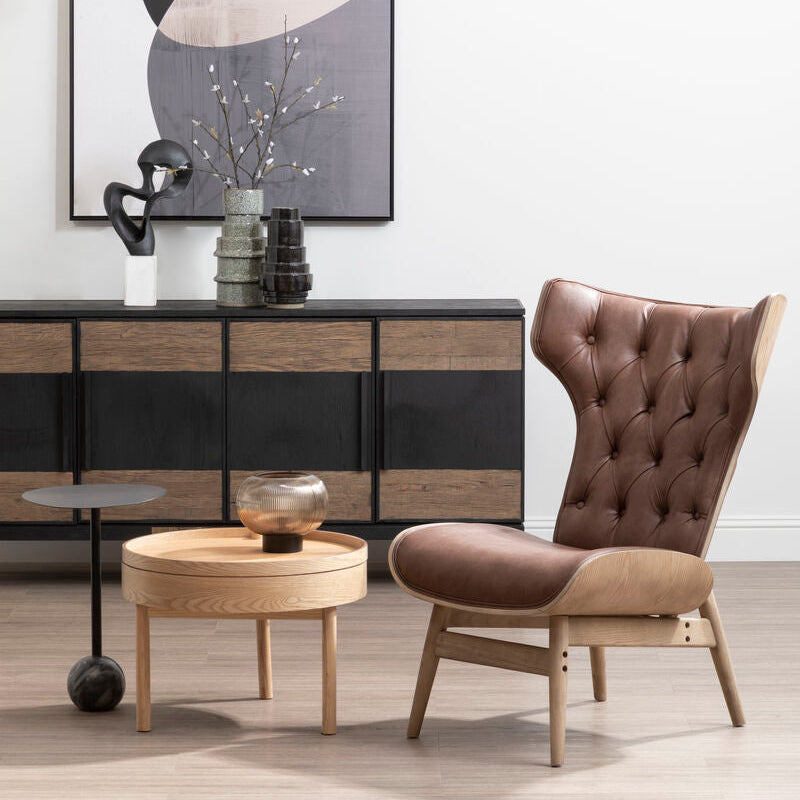Modern interior with a brown chair, side table, and abstract art on a white wall.